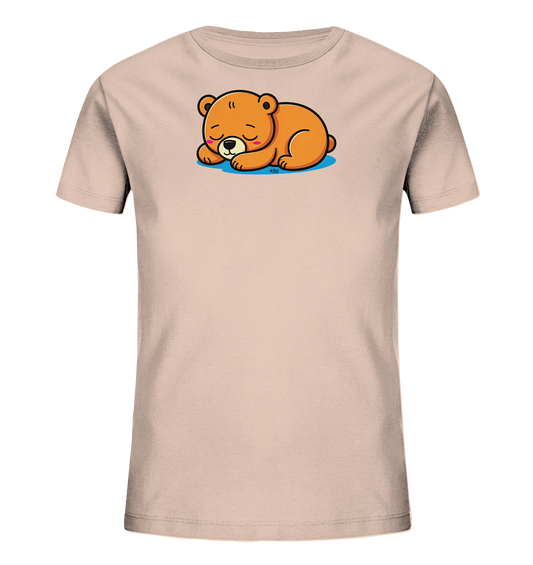 Onlineshop Shirts fuer Kinder - Das Bild zeigt ein hellbeiges Kinder-T-Shirt. Auf der Vorderseite ist eine friedlich schlafende, braune Baerenfigur abgebildet, die auf einer blauen Flaeche ruht. Das Design ist liebevoll und weckt eine ruhige, entspannte Atmosphaere. Das T-Shirt hat kurze Ärmel und einen klassischen Rundhalsausschnitt.