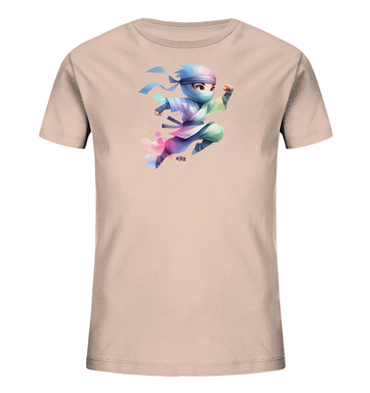 Onlineshop Shirts fuer Kinder - Das Bild zeigt ein hellrosa Kinder-T-Shirt mit einem dynamischen Druck auf der Vorderseite. Darauf ist eine stilisierte Comicfigur in Ninja-Pose abgebildet, die in bunten Farben gestaltet ist. Die Figur scheint zu springen und wird von farbigen Aquarell-Flecken umgeben. Das Design wirkt lebhaft und farbenfroh.