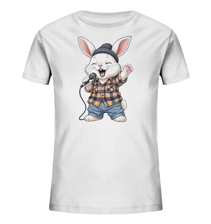 Onlineshop Shirts fuer Kinder - Das Bild zeigt ein weisses Kinder-T-Shirt mit einem lebhaften Motiv eines singenden Hasen. Der Hase traegt eine dunkle Muetze, ein kariertes Hemd und Jeans, waehrend er ein Mikrofon haelt und begeistert singt. Seine Pfote ist erhoben und sein Mund ist geoeffnet, was eine froehliche und musikalische Stimmung vermittelt. Das Design ist verspielt und farbenfroh, ideal fuer Kinder.