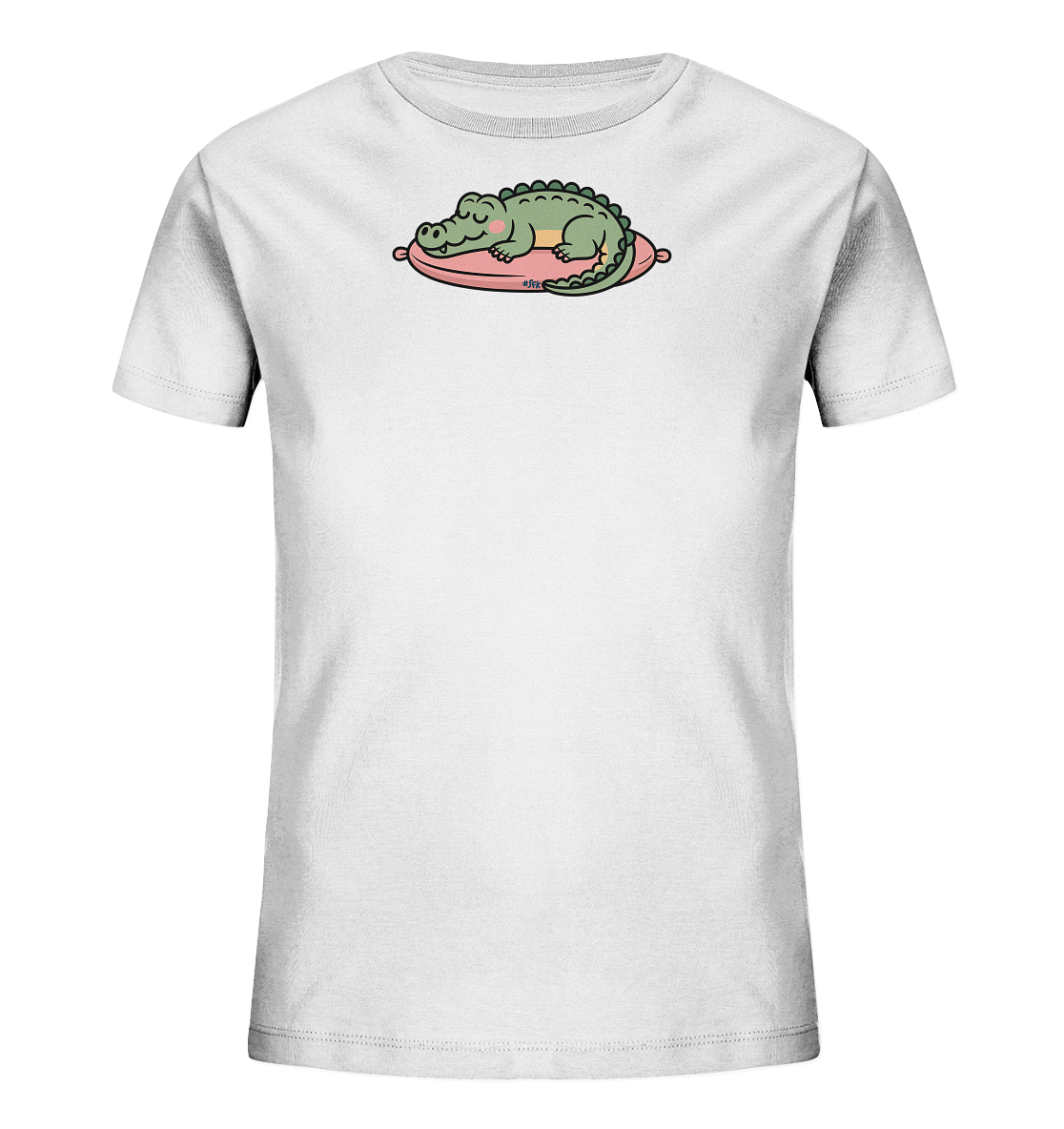 Onlineshop Shirts fuer Kinder - Das Bild zeigt ein weisses Kinder-T-Shirt mit einem niedlichen Aufdruck eines schlafenden Krokodils. Das gruene Krokodil ruht friedlich auf einem pinkfarbenen Kissen mit einem hellen Streifen. Es hat geschlossene Augen und rosafarbene Wangen, was ihm einen sanften Ausdruck verleiht. Das Motiv wirkt verspielt und kindgerecht.