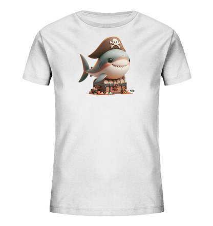 Onlineshop Shirts fuer Kinder - Das Bild zeigt ein weisses Kindershirt mit einem grossen Grafikdruck auf der Vorderseite. Das Design zeigt einen niedlichen, laechelnden Cartoon-Hai mit braunem Piratenhut und Totenkopf-Emblem. Der Hai sitzt auf einer hoelzernen Schatzkiste, umgeben von Muscheln und Sand. Die Gesamtillustration hat ein verspieltes und abenteuerliches maritimes Thema.
