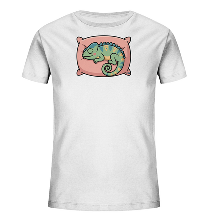 Onlineshop Shirts fuer Kinder - Das Bild zeigt ein weisses T-Shirt fuer Kinder. Auf der Vorderseite ist ein niedliches, schlafendes Chamaeleon abgebildet, das auf einem rosafarbenen Kissen liegt. Das Chamaeleon ist gruen-blau gefaerbt mit gelben Akzenten und hat seinen Schwanz eingerollt. Dieses Motiv verleiht dem Shirt einen ruhigen und verspielten Charakter.