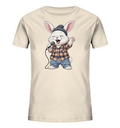 Onlineshop Shirts fuer Kinder - Das Bild zeigt ein cremefarbenes Kinder-T-Shirt mit einem niedlichen Cartoon-Hase. Der Hase traegt eine Muetze, ein kariertes Hemd und Jeans und haelt ein Mikrofon. Er scheint begeistert zu singen, mit geoeffnetem Mund und einer erhobenen Pfote. Das Design strahlt Freude und musikalische Energie aus.