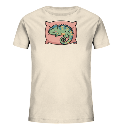 Onlineshop Shirts fuer Kinder - Das Bild zeigt ein hellbeiges Kinder-T-Shirt mit einem niedlichen Motiv. Darauf ist ein schlafendes Chamaeleon in Gruen- und Blautoenen zu sehen, das gemuetlich auf einem rosa Kissen liegt. Das Chamaeleon hat gelbe Muster und einen eingerollten Schwanz, was dem Design eine entspannte und verspielte Note verleiht.