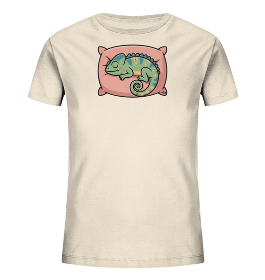 Onlineshop Shirts fuer Kinder - Das Bild zeigt ein hellbeiges Kinder-T-Shirt mit einem niedlichen Motiv. Darauf ist ein schlafendes Chamaeleon in Gruen- und Blautoenen zu sehen, das gemuetlich auf einem rosa Kissen liegt. Das Chamaeleon hat gelbe Muster und einen eingerollten Schwanz, was dem Design eine entspannte und verspielte Note verleiht.