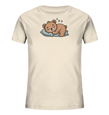 Onlineshop Shirts fuer Kinder - Das Bild zeigt ein beigefarbenes T-Shirt fuer Kinder mit einem niedlichen Motiv. Darauf ist ein kleiner brauner Baer abgebildet, der friedlich auf einem hellblauen Kissen schlaeft. Über dem Baerenkopf sind Zzz-Zeichen zu sehen, die seinen Schlaf symbolisieren. Das Design wirkt beruhigend und verspielt, ideal fuer ein Kinderoutfit.