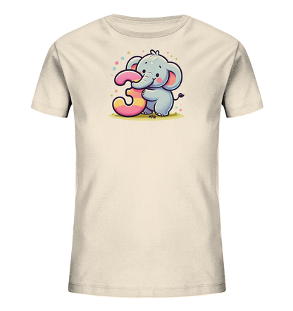 Onlineshop Shirts fuer Kinder - Dieses cremefarbene T-Shirt zeigt eine niedliche Illustration eines kleinen, laechelnden Elefanten. Der Elefant umarmt eine grosse, bunte Zahl 3 mit pinken und gelben Streifen. Die Grafik ist von farbigen Konfetti-Punkten umgeben und steht auf einer gruenen Grasflaeche. Das Design wirkt froehlich und verspielt.