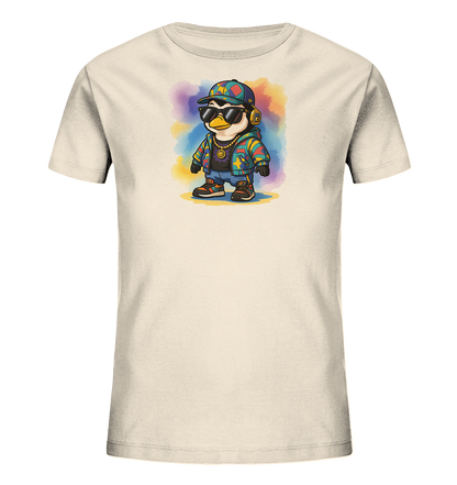 Onlineshop Shirts fuer Kinder - Das Bild zeigt ein beiges Kinder-T-Shirt mit einem stylischen Pinguin-Motiv. Der Pinguin traegt Sonnenbrille, Kopfhoerer, eine bunte Kappe, eine Goldkette und eine farbenfrohe Jacke. Im Hintergrund des Motivs befindet sich ein Aquarell-Effekt in verschiedenen Farbtoenen. Das Gesamtbild ist lebhaft und modern gestaltet.