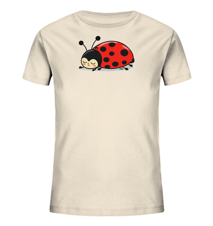 Onlineshop Shirts fuer Kinder - Das Bild zeigt ein cremefarbenes Kinder-T-Shirt mit einem niedlichen Marienkaefer-Motiv auf der Vorderseite. Der Marienkaefer ist rot mit schwarzen Punkten und hat einen schwarzen Kopf mit Fuehlern. Er liegt schlafend da, mit geschlossenen Augen und einem sanften Laecheln. Das Design wirkt verspielt und friedlich.