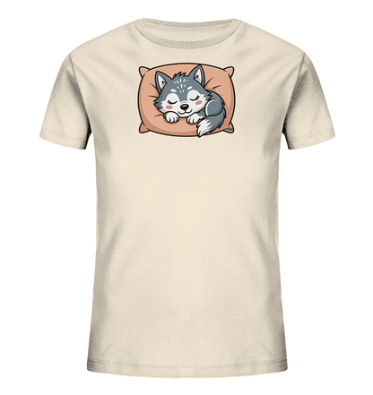 Onlineshop Shirts fuer Kinder - Das Bild zeigt ein cremefarbenes Kinder-T-Shirt mit einem niedlichen Aufdruck auf der Vorderseite. Darauf ist ein schlafender Wolfswelpe zu sehen, der gemuetlich auf einem hellrosa Kissen liegt. Der Welpe ist grau mit weissen Akzenten und geschlossenen Augen, was einen ruhigen und friedlichen Ausdruck verleiht. Das Design wirkt liebevoll und ansprechend fuer Kinder.
