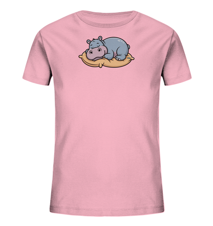Onlineshop Shirts fuer Kinder - Das Bild zeigt ein hellrosa Kinder-T-Shirt mit einem niedlichen Aufdruck auf der Vorderseite. Darauf ist ein cartoonartiges, blau-graues Nilpferd zu sehen, das friedlich auf einem gelben Kissen schlaeft. Das Nilpferd hat geschlossene Augen und rosafarbene Wangen, was einen entspannten Ausdruck verleiht. Das Design wirkt verspielt und ansprechend fuer Kinder.