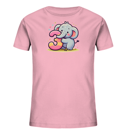 Onlineshop Shirts fuer Kinder - Das Bild zeigt ein rosafarbenes T-Shirt fuer Kinder. Darauf ist ein niedlicher, grauer Cartoon-Elefant abgebildet, der die grosse Zahl '3' haelt. Die Zahl ist pink und gelb gestreift und wird von bunten Punkten umgeben. Das Motiv wirkt froehlich und ist ideal fuer kleine Kinder.