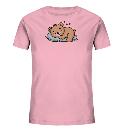 Onlineshop Shirts fuer Kinder - Das Bild zeigt ein rosafarbenes Kinder-T-Shirt mit einem suessen Motiv eines schlafenden Teddybaeren. Der braune Baer liegt friedlich auf einem hellblauen Kissen, die Augen geschlossen, mit 'Zzz'-Symbolen ueber seinem Kopf. Dieses Design verleiht dem Shirt einen ruhigen und behaglichen Ausdruck. Es ist eine liebevolle Darstellung, die zum Entspannen einlaedt.