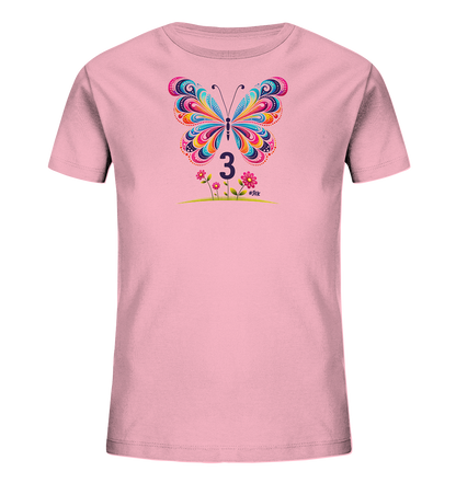 Onlineshop Shirts fuer Kinder - Das Bild zeigt ein rosa T-Shirt fuer Kinder mit einem auffaelligen, bunten Schmetterling auf der Vorderseite. Der Schmetterling besticht durch detailreiche, farbenfrohe Muster auf seinen Fluegeln. Unter dem Schmetterling ist die Zahl '3' platziert, begleitet von stilisierten Blumen und einer gruenen Wiese. Das Design wirkt insgesamt lebhaft und kinderfreundlich.