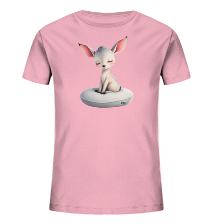 Onlineshop Shirts fuer Kinder - Das Bild zeigt ein hellrosa Kinder-T-Shirt. Auf der Vorderseite befindet sich eine reizende Illustration eines hellfarbigen, grossohrigen Wesens mit einem gelassenen Ausdruck. Dieses Wesen sitzt ruhig auf einem weichen, weissen, ringfoermigen Kissen. Das gesamte Design vermittelt einen friedlichen und sanften Charakter.